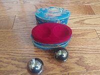 Open brocade case showing red velvet insert and two metal Baoding balls