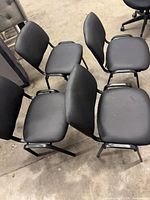 Top view showing four black stackable chairs with padded seats and backs