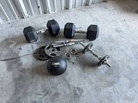 All items laid out on floor: three hex dumbbells, spin-lock handles, plates, collars, medicine ball
