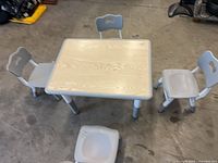 Top view of table and three chairs showing laminate top and plastic construction