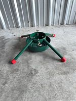 Overall view of green metal stand with four legs and red caps
