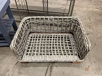 Woven wicker basket in foreground; metal-frame bench and rack visible behind giving context and scale