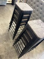 Two stacks of four black metal stools with wood seats