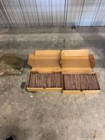 Two open boxes filled with thin brick veneer tiles on concrete floor