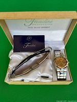 Gift set in wooden box showing sunglasses, watch, guarantee card and extra link