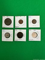 Front view six coins in holders with handwritten labels