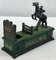Full left-side view of cast iron showjumper bank showing base text, horse and rider, finish gate