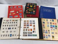Seven stamp albums on table, two open showing stamp pages