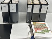 Front view of five labeled binders and open binder showing stamp pages
