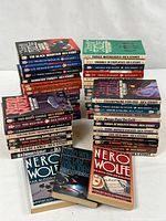 Front and side view of two stacks of Nero Wolfe paperbacks, showing uniform size and cover art