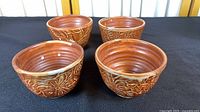Four ceramic bowls, brown raku glaze, textured exterior