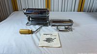 Pasta maker with crank handle inserted, table clamp and booklet displayed
