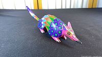 Full side view of painted wooden armadillo alebrije showing overall shape, colours and tail