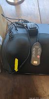 Black back massager showing shape, wired remote and AC adapter