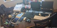 Overview of entire lot on table showing laptops, tablets, Game Boy, GoPro, keyboards, mouse and accessories