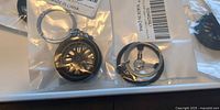 Close-up of two bagged keychains showing wheel rim and steering wheel designs