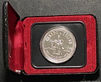 Closed display case opened to show housed coin