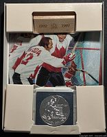 Coin in capsule within presentation packaging showing wooden insert dated 1972-1997