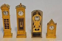 Group shot of four gold tone miniature clocks showing relative sizes and styles