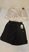 Two DSG run shorts, one black, one cream/tie-dye, both with tags visible