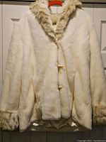 Full front view of white faux fur jacket on hanger
