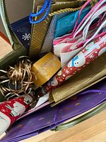 Top view of green tote containing wrapping paper rolls, gift bags, tissue paper, raffia ribbon, yellow gift box