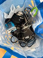 Top view into blue tote showing batteries, cables, phone cradles, adapters and other electronics