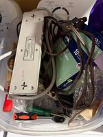 Overview of entire lot inside plastic bin showing Leviton outlet boxes, power bar, cords and tools