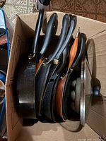 Box containing five frying pans/skillets with two glass lids