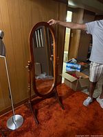 Front view of oval cheval mirror showing wooden frame, turned supports, base and overall condition