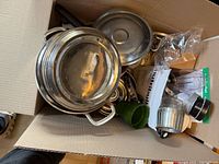 Box containing stainless pots, NutriBullet cups, blade, utensils