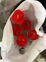 Top view of six clear glass jars with red lids inside tote bag