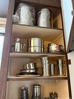 Cabinet shelves showing tumblers, canister, jug, tiffin, small trays