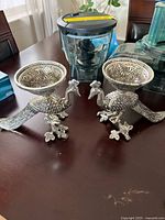 Pair of silver-tone peacock candle holders on tabletop
