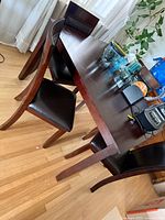 Dark wood dining table with four chairs showing black faux leather seats and overall finish