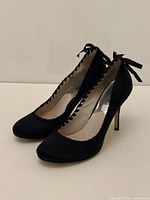 Side view of both shoes showing satin material, scalloped edge, heel height