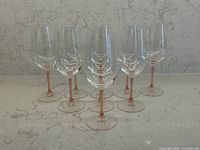 Front view showing all nine glasses with pink stems