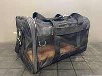 Three-quarter view showing quilted shell, mesh sides, handles, shoulder strap, brown pad inside