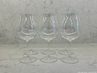 Front view of six clear Riedel Burgundy wine glasses