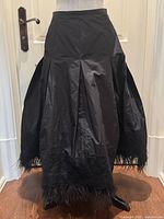 Front view of black taffeta skirt showing pleats, lace band and feather hem