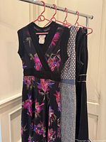 Four dresses hanging on pink hangers showing overall styles and colours