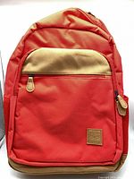 Front view showing red body, tan pocket panel, zipper pulls, Canada 150 patch