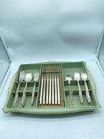 Entire flatware set arranged in green plastic tray