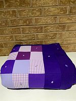 Quilt folded showing purple patchwork front