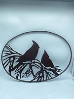 Front view showing entire oval steel wall art with cardinal silhouettes