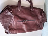 Side view showing leather exterior, handles, exterior zip pocket