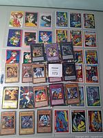 Overall view of binder pages and loose cards showing Yu-Gi-Oh, Marvel and anime cards