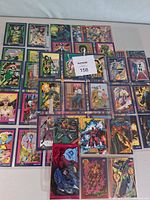Overview of entire lot showing multiple Marvel and DC trading cards spread out