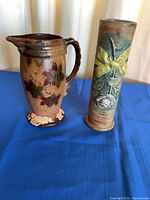 Pitcher and vase side by side on blue surface