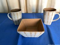 Front view of two mugs and square bowl showing pattern and color